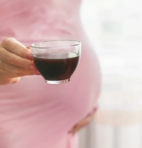 беременная женщина с чашкой кофе в руке